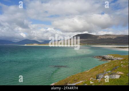 Luskentire Beach vom Aussichtspunkt bei Seilebost. Blauer Himmel und Wolken, türkisfarbenes Meerwasser, weißer Sand, Gras, Felsen, Berge im Hintergrund. Harris. Stockfoto