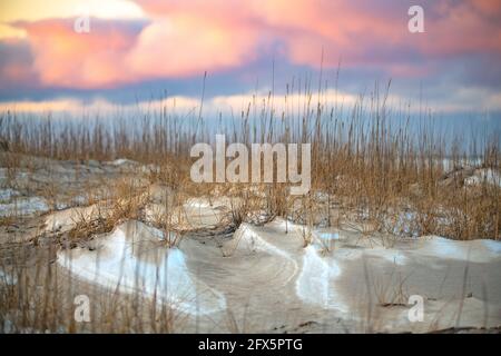 Atemberaubender rosafarbener Sonnenuntergang über der eisigen Küste der Hudson Bay im Norden von Manitoba, wenn der Schnee gefallen ist und sich mit Sandverwehungen vermischt hat. Stockfoto