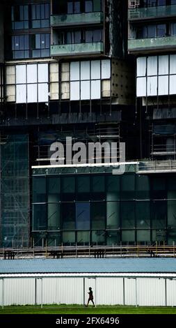 Lady, die allein unter einem riesigen Gebäude in Singapur herumläuft Stockfoto