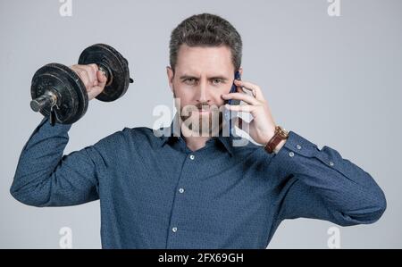 Gutaussehender Geschäftsmann mit Hantel sprechen am Telefon. Digitaler Sport. Stockfoto