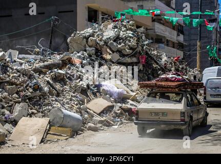 Gaza, Palästina. Mai 2021. Ein Auto fährt in der Nähe der Trümmer eines zerstörten Gebäudes nach dem Waffenstillstand zwischen Israel und den Aktivisten des Gazastreifens vorbei. DER US-Spitzendiplomat Antony Blinken schwor Unterstützung beim Wiederaufbau des zerrütteten Gazastreifens und bei der Unterstützung eines Waffenstillstands zwischen der Hamas und Israel, bestand aber darauf, dass die militanten islamistischen Herrscher des Territoriums von keiner Hilfe profitieren würden. Kredit: SOPA Images Limited/Alamy Live Nachrichten Stockfoto