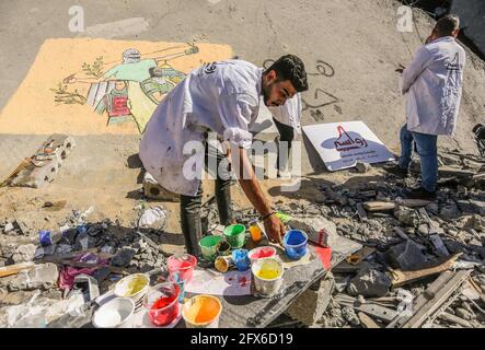 Gaza, Palästina. Mai 2021. Palästinensische Künstler malen Wandmalereien auf eingestürzte Gebäude nach den israelischen Streiks in Gaza. DER US-Spitzendiplomat Antony Blinken schwor Unterstützung beim Wiederaufbau des zerrütteten Gazastreifens und bei der Unterstützung eines Waffenstillstands zwischen der Hamas und Israel, bestand aber darauf, dass die militanten islamistischen Herrscher des Territoriums von keiner Hilfe profitieren würden. Kredit: SOPA Images Limited/Alamy Live Nachrichten Stockfoto