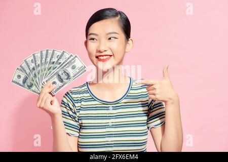 Foto von reichen Frau in Grundkleidung hält Fan von Dollar Geld isoliert über rosa Hintergrund Stockfoto