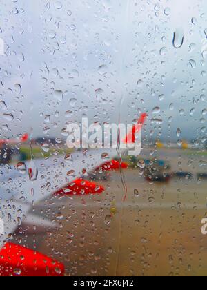 Wassertropfen auf dem Flugzeugfensterglas, selektiver Fokus. Selektiver Fokus Regen Tropfen Form Fenstersitz im Flugzeug mit verschwommenem Flügelhintergrund Stockfoto