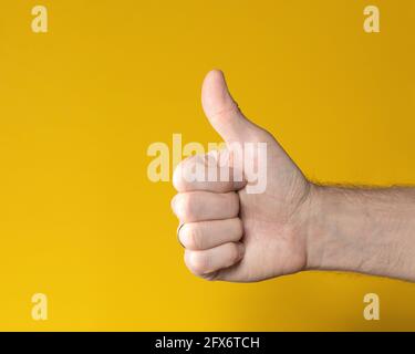 Mann Hand mit Daumen nach oben isoliert auf gelbem Hintergrund. Mit „Gefällt mir“-Zeichen. Symbol, Symbol für perfekt oder akzeptieren. Stockfoto