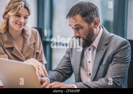 Überraschte den Mann, der am Laptop arbeitete und einen Angestellten flirtet Stockfoto
