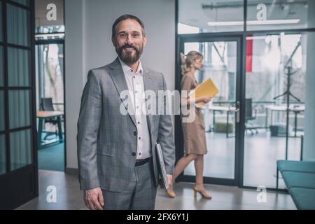 Glücklicher Mann im Anzug und Frau, die hinter sich hergeht Stockfoto