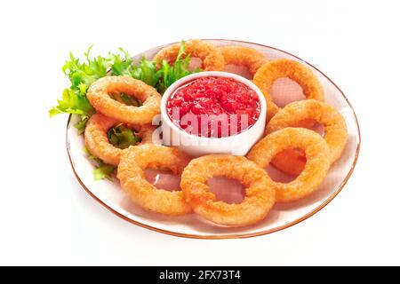 Calamari-Ringe, isoliert. Frittierte Tintenfischringe mit grünen Salatblättern und Marinara-Sauce auf weißem Hintergrund Stockfoto