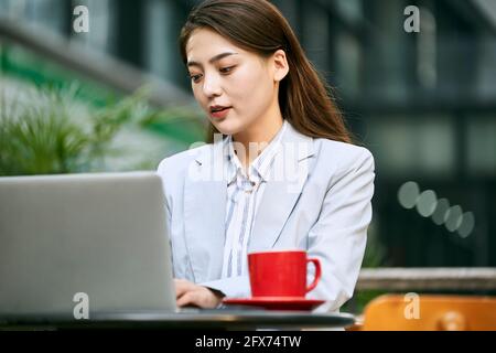 Junge asiatische Geschäftsfrau, die mit einem Laptop im Café im Freien arbeitet Computer Stockfoto