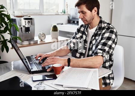 Mann, der im Heimbüro mit einem Laptop arbeitet. Online-Geschäftskonzept. Remote-Arbeit Stockfoto