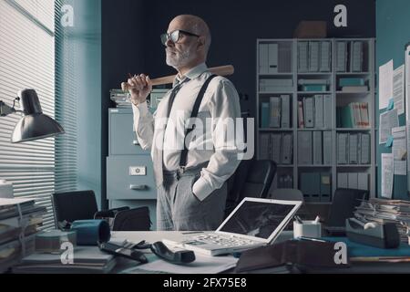 Wütend gestresster Geschäftsmann im Büro: Er zerstörte seinen Laptop mit einem Baseballschläger Stockfoto