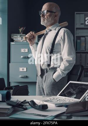 Wütend gestresster Geschäftsmann im Büro: Er zerstörte seinen Laptop mit einem Baseballschläger Stockfoto