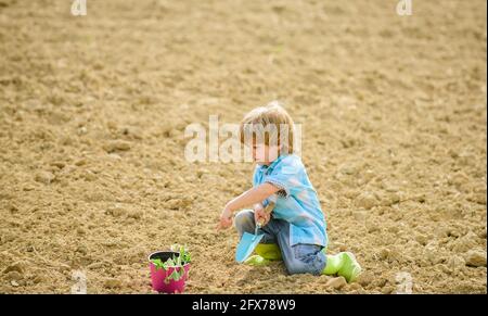 Tag der Erde. Neues Leben. Sommerfarm. Ökologisches Leben. Mensch und Natur. Glücklicher Kindergärtner. Pflanzenkindergarten. Frühling. Kleines Kind Pflanzen eine Blume. Bio Stockfoto