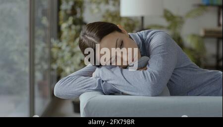 Deprimierte junge Frau, die zu Hause auf der Couch liegt, Stress und psychisches Gesundheitskonzept Stockfoto