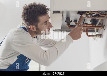 Professioneller Installateur, der einen Kessel und Rohre überprüft, Kesselservicekonzept Stockfoto