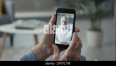 Älterer Mann, der seinen Online-Arzt von zu Hause aus anruft, telemedizinisches Konzept Stockfoto