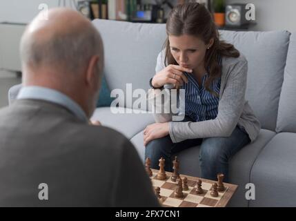 Zwei Personen, die zu Hause im Wohnzimmer Schach spielen, konzentrieren sich auf das Spiel Stockfoto