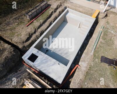 Drohnenaufnahme der Poolbaustelle, auf der der Pool bereits fertig gefüllt, ohne Folie verputzt in einem Garten in österreich ist Stockfoto
