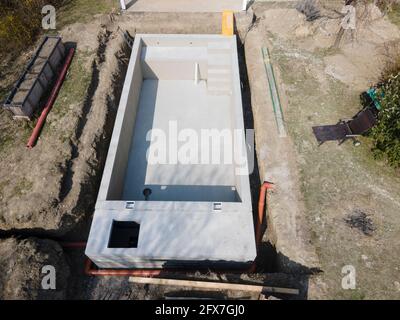 Drohnenaufnahme der Poolbaustelle, auf der der Pool bereits fertig gefüllt, ohne Folie verputzt in einem Garten in österreich ist Stockfoto