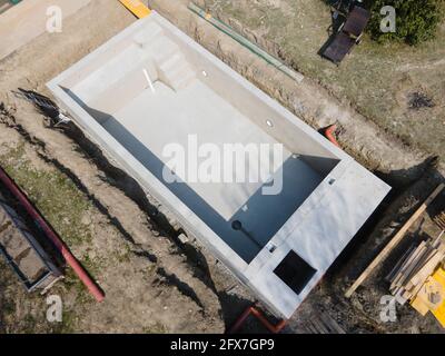 Drohnenaufnahme der Poolbaustelle, auf der der Pool bereits fertig gefüllt, ohne Folie verputzt in einem Garten in österreich ist Stockfoto