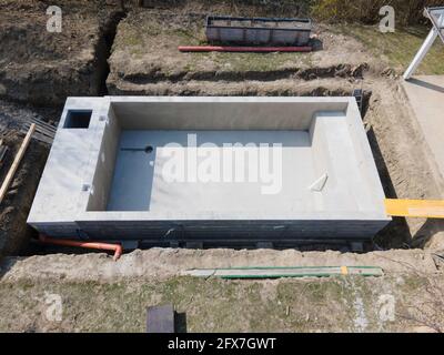 Drohnenaufnahme der Poolbaustelle, auf der der Pool bereits fertig gefüllt, ohne Folie verputzt in einem Garten in österreich ist Stockfoto