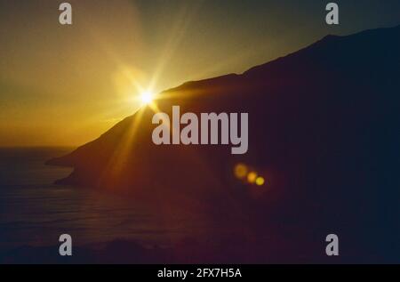 Archivbild. Starburst der Sonne in der Nähe von Sonnenuntergang über Klippen an der Südküste von Kreta, Griechenland genommen 1979 Stockfoto