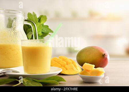 Frühstück mit natürlichem Mangosaft mit Milch auf einer Küchenbank mit geschnittenem Obst. Vorderansicht. Stockfoto
