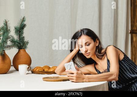 Nette afroamerikanische Frau, die Nachrichten auf dem Smartphone liest Küche Stockfoto