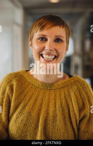 Glückliche weibliche Führungskraft im Büro. Schöne junge Geschäftsfrau lächelt vor der Kamera. Stockfoto