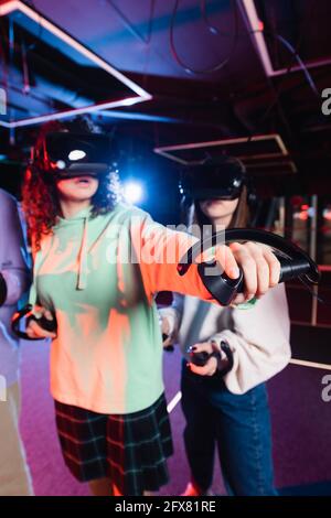 afroamerikanisches Mädchen in vr Headset-Gaming in der Nähe verschwommene Freunde Stockfoto