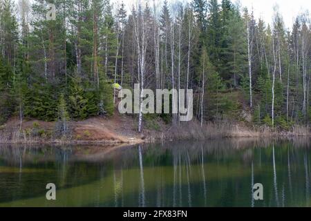 Gelbes Zelt am steilen Ufer eines kleinen Waldsees an einem Frühlingstag, Russland. Stockfoto