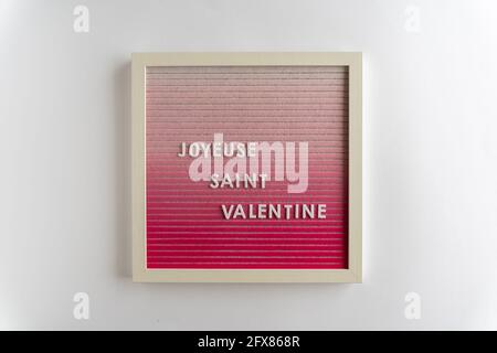 Rosa Brieftafel-Worte, die Joyeuse Saint Valentin (Übersetzung: Happy Valentines), auf weißem Hintergrund, horizontal Stockfoto