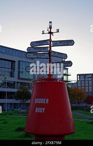 DUBLIN, IRLAND - 27. Oktober 2019: Vertikale Aufnahme der Dodder Boje im Grand Canal Dock, Dublin, Irland. Der Wegweiser zeigt Richtungen und Entfernungen zu an Stockfoto
