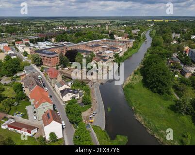 26. Mai 2021, Brandenburg, Guben: Ansicht der Baustelle für den weiteren Bau des Hochwasserschutzes am linken Ufer der deutsch-polnischen Grenzfluß Neisse (Luftaufnahme mit Drohne). Dadurch wird der Hochwasserschutz in der Stadt weiter verbessert. Derzeit bieten der vorhandene Deich und die sanierungsbedürftige Uferwand im Bereich des Plastinariums für das Stadtgebiet Guben im Bereich der Alten Poststraße mit der aktuellen Kronenhöhe keinen ausreichenden Hochwasserschutz. Zudem besteht eine weitere potenzielle Gefahr durch das Rückwasser der Lausitzer Neiße Stockfoto