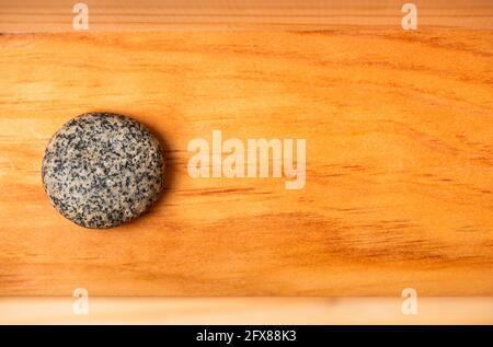 Stück aus rundem Marmorstein auf einer Holzfläche Stockfoto