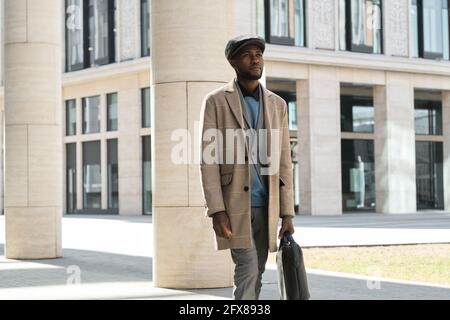 Afrikanischer junger Mann, der in der Stadt die Straße entlang läuft Stockfoto