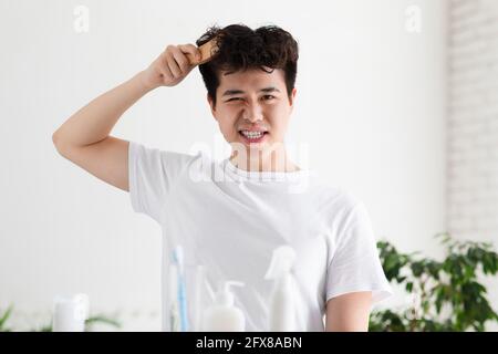 Asian gut aussehend junger Mann in weißem T-Shirt kombiniert mit Bürste Stockfoto