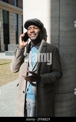 Afrikanischer junger Geschäftsmann, der auf dem Mobiltelefon spricht, während er auf dem Telefon steht Die Straße Stockfoto