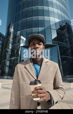 Porträt eines afrikanischen Mannes, der die Kamera anschaut und Kaffee trinkt Während Sie in der Stadt stehen Stockfoto
