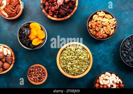 Nüsse und getrocknete Früchte. Getrocknete Aprikosen, Feigen, Rosinen, Pekannüsse, Walnüsse, Haselnüsse, Mandeln und andere. Blauer Hintergrund, Draufsicht Stockfoto