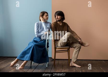 Kerl und Mädchen sitzen auf Stühlen nahe beieinander. Stockfoto