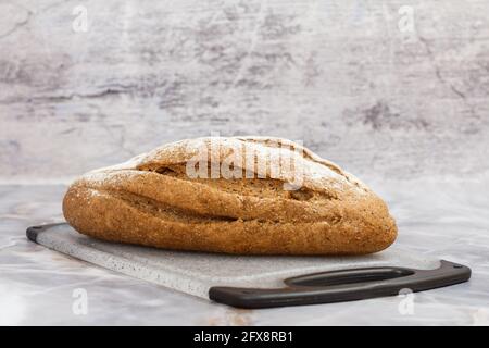 Brot auf Schneidebrett mit grauem Hintergrund Stockfoto