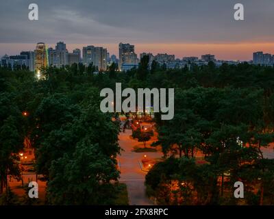 Erstaunlich ruhiger entspannender, farbenfroher Abend in Kiew (Kiew). Gebäude, Beobachtungsrad und Kuppelkirche am Horizont. Industrielles Stadtbild. Stockfoto