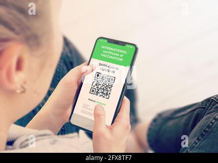 COVID-19: Digitale grüne Zertifikate auf dem Handy-Bildschirm. Junges Mädchen nimmt Smartphone mit geimpften digitalen Gesundheitspass. Stockfoto