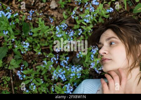 Mädchen auf der Wiese von Forget-Me-Nots hat viel Platz auf der Seite. Die Augen sind offen. Stockfoto