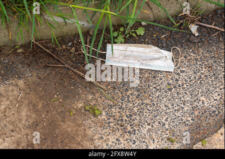 Alte gebrauchte Einweg-Gesichtsmaske, die auf dem Gelände eines NHS-Krankenhauses von Norfolk weggeworfen wurde. Stockfoto