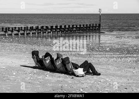 Vier Personen sonnen sich Mitte April an der Nordsee in Bridlington, East Riding of Yorkshire, England. Farbversion 2FX8WD0 Stockfoto