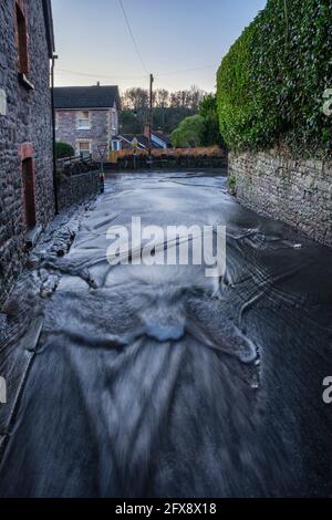 Regenwasser fließt die Trellech Straße hinunter in Tintern. Stockfoto