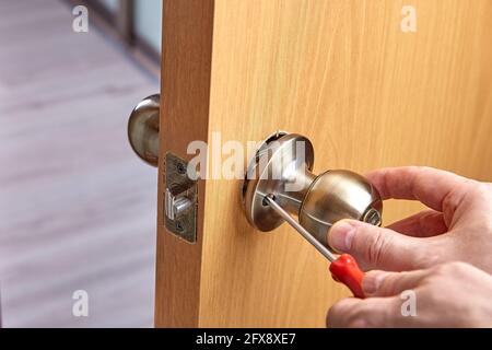 Reparatur des Türgriffs mit Schloss und Verriegelung, mit Schraubendreher. Stockfoto