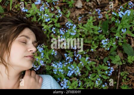 Mädchen auf der Wiese von Forget-Me-Nots hat viel Platz auf der Seite. Die Augen sind geschlossen. Stockfoto